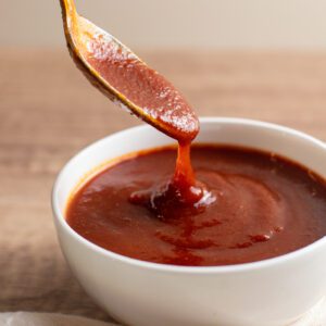 photo of a spoon dipping in a bowl of sweet and tangy bbq sauce