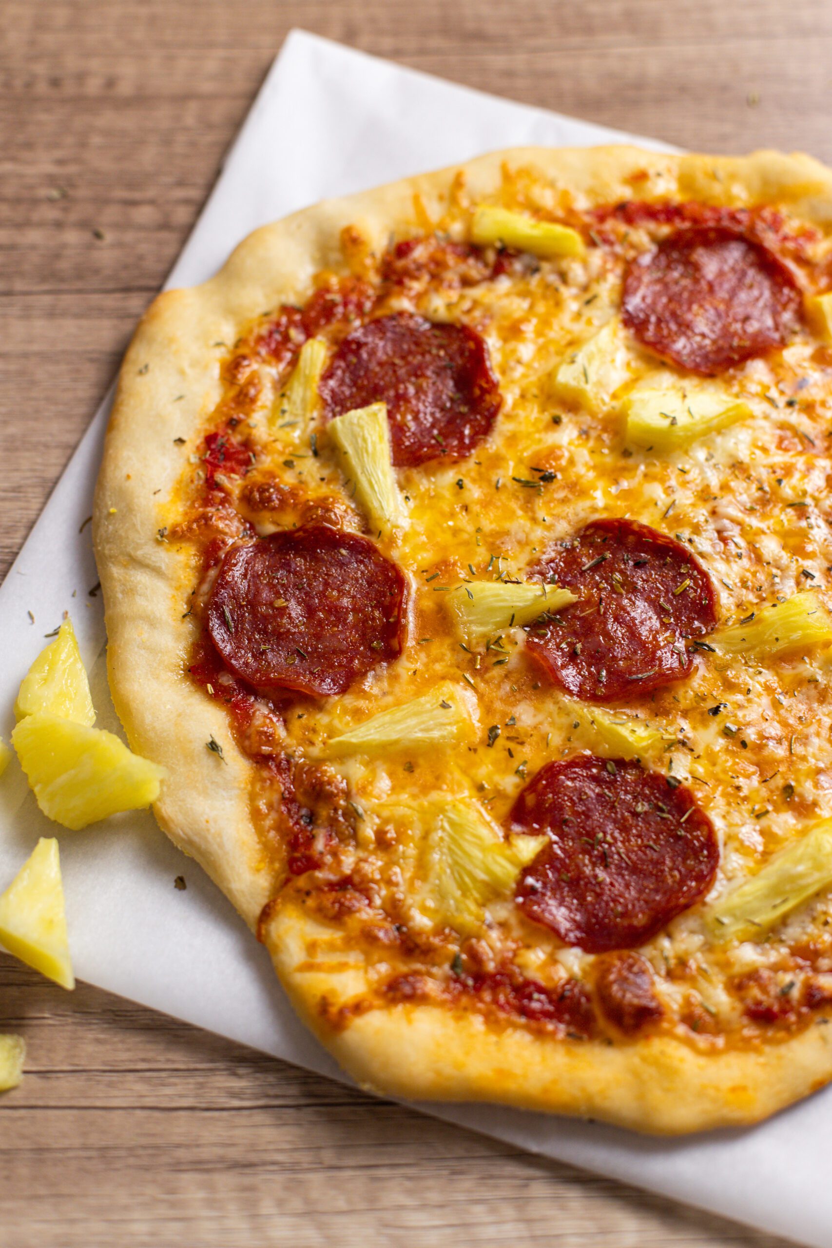 pineapple pepperoni pizza on a wooden board