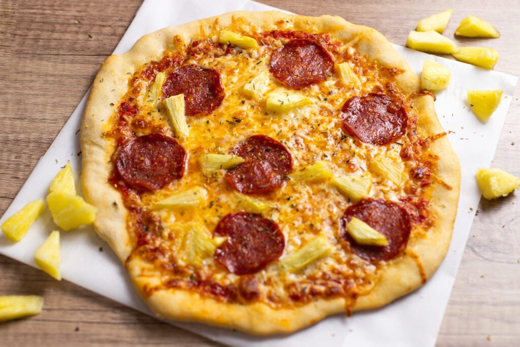 pepperoni pizza with pineapple sitting on wood