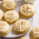 Sour cream cookies with maple buttercream frosting sitting on plate with milk