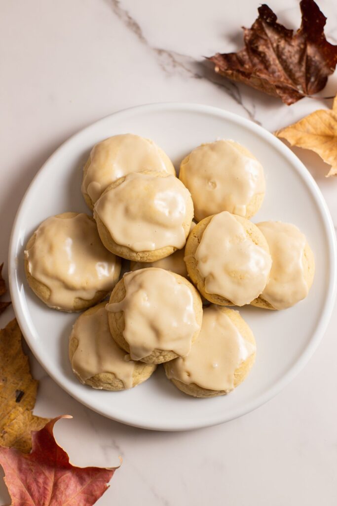 maple cookies with maple icing sitting on plate with maple leaves