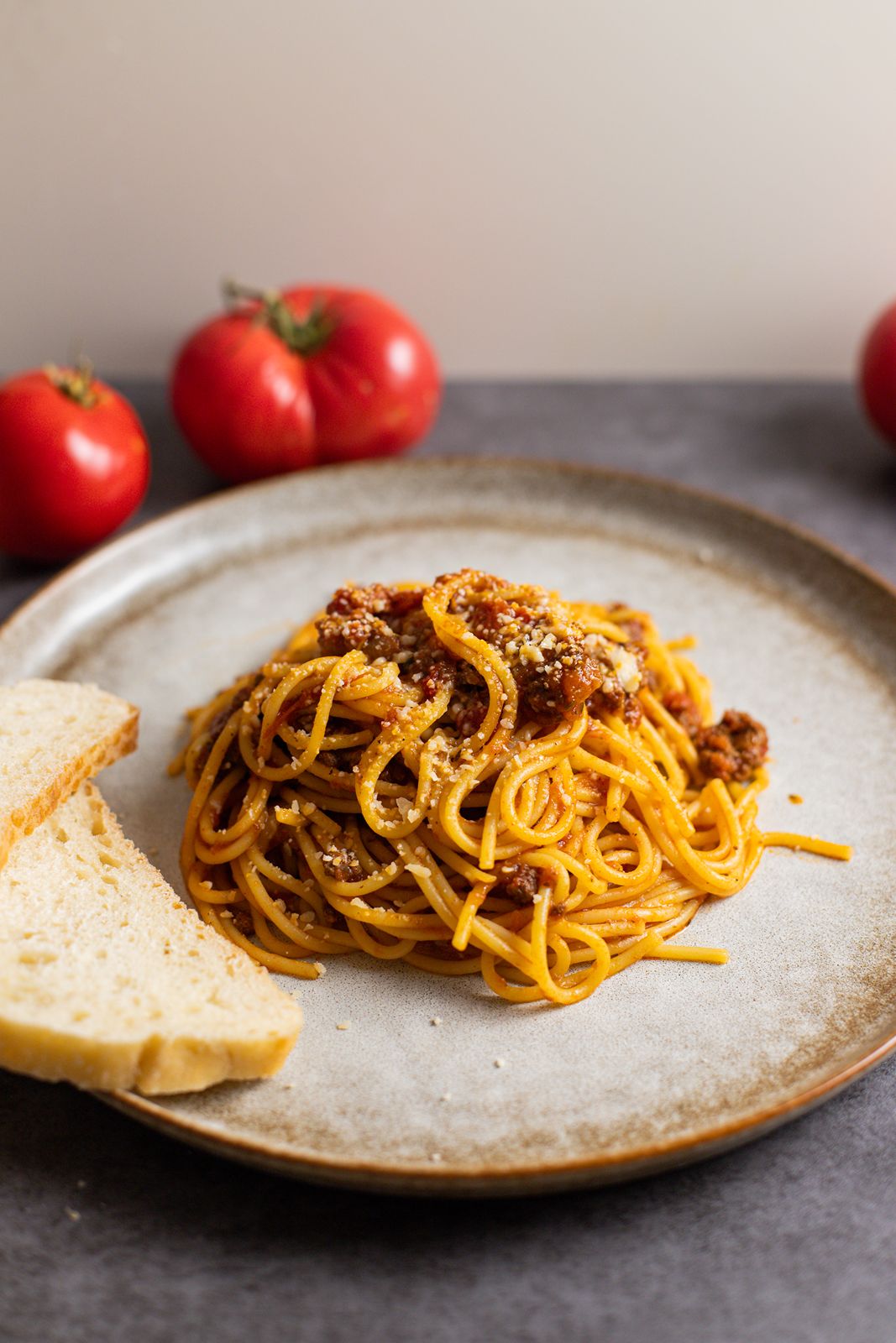 Slow cooker beef pasta sauce on a plate with tomatoes and bread