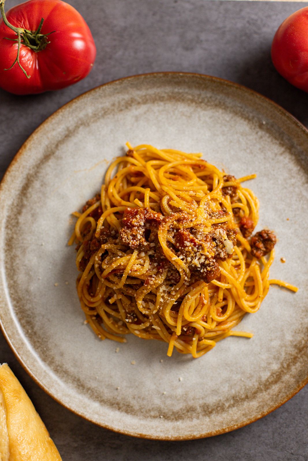 The best slow cooker beef pasta sauce on a plate with tomatoes and bread