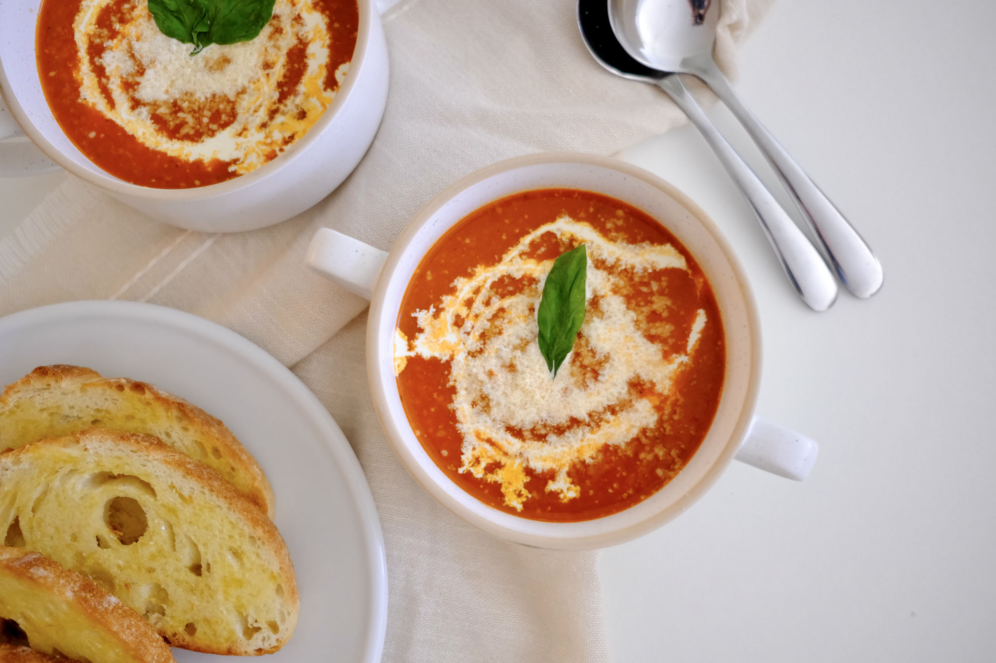 Roasted tomato vegetable soup served with grilled cheese on a white plate—classic comfort food pairing.