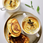 butternut squash soup with roasted garlic​ in a bowl on a plate