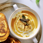 butternut squash soup with roasted garlic​ in a bowl on a plate