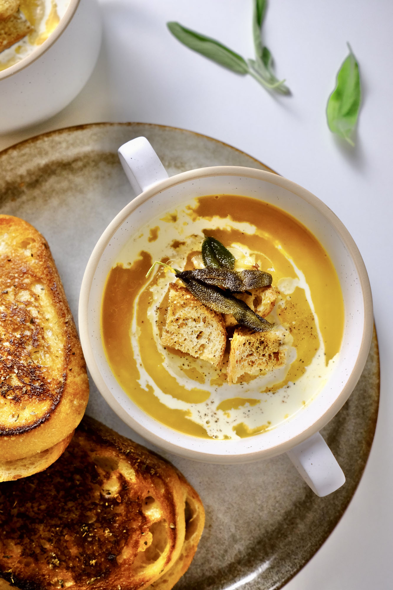 butternut squash soup with roasted garlic​ in a bowl on a plate