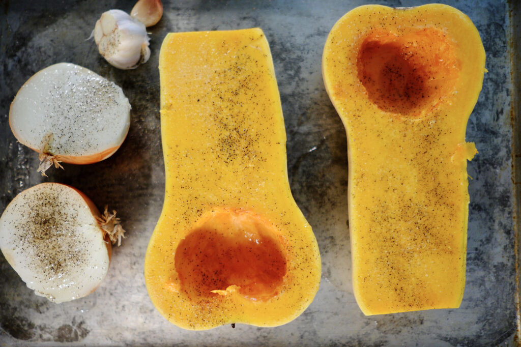 butternut squash cut in half and prepped for roasted butternut squash soup with roasted garlic