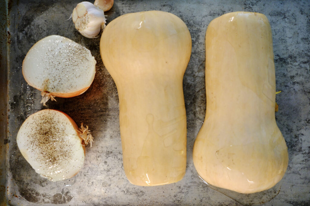 butternut squash cut in half and prepped for roasted butternut squash soup with roasted garlic