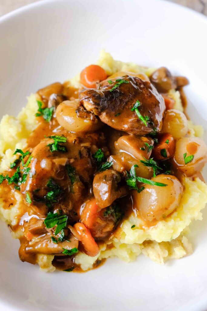 slow cooker coq au vin in a bowl with mashed potatoes
