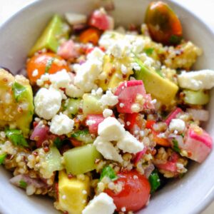 quinoa rainbow salad with tomatoes, cucumbers, avocado, peppers, and vinaigrette dressing