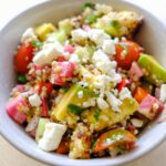 quinoa rainbow salad with tomatoes, cucumbers, avocado, peppers, and vinaigrette dressing