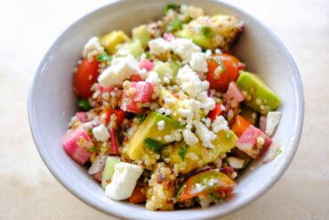 quinoa rainbow salad with tomatoes, cucumbers, avocado, peppers, and vinaigrette dressing
