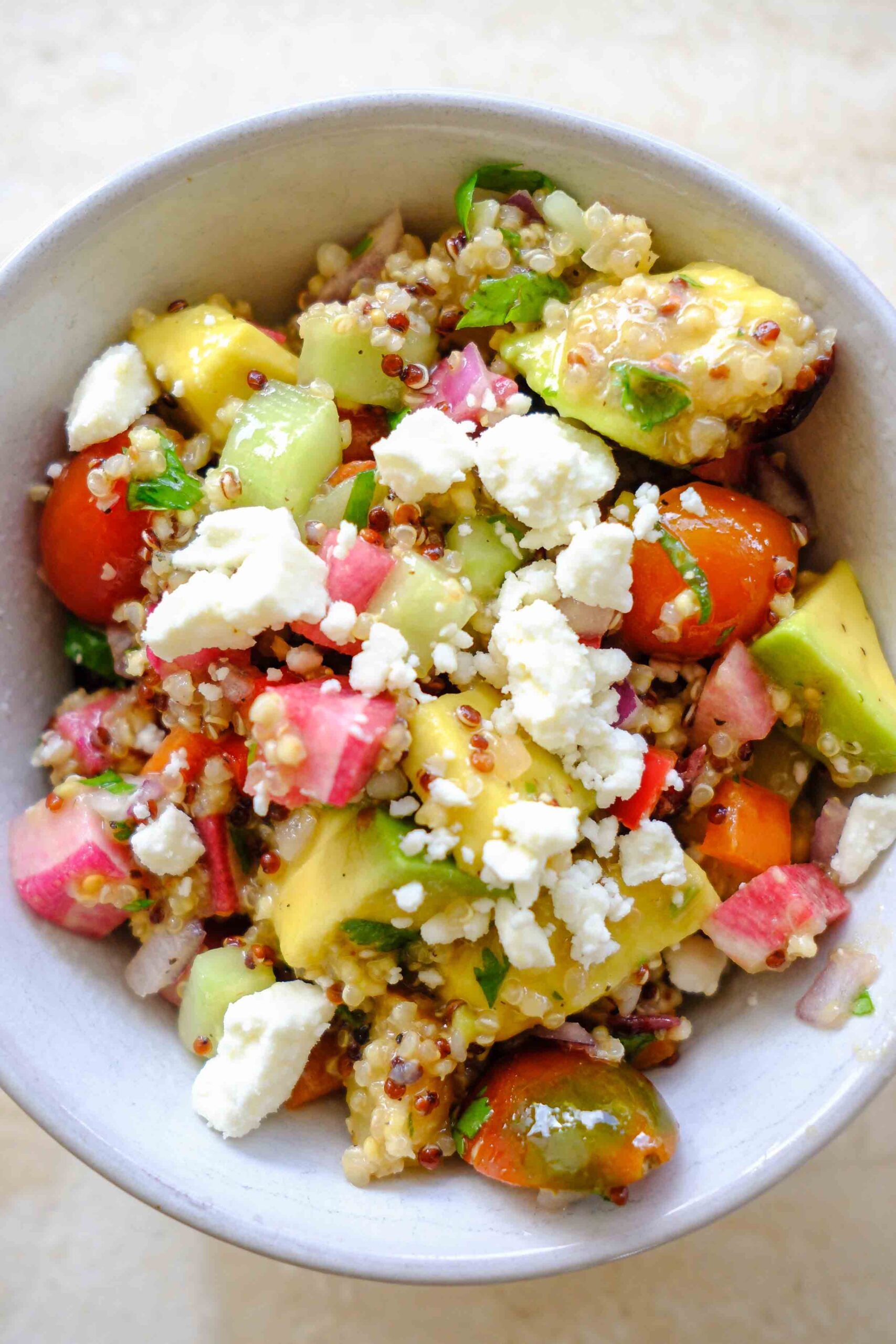 rainbow quinoa salad with tomatoes, cucumbers, avocado, peppers, and vinaigrette dressing