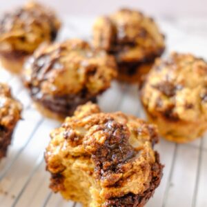 cottage cheese cinnamon muffin bitten and on a plate with other muffins behind it