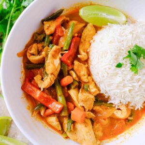 red thai chicken curry in a bowl with cilantro and lime